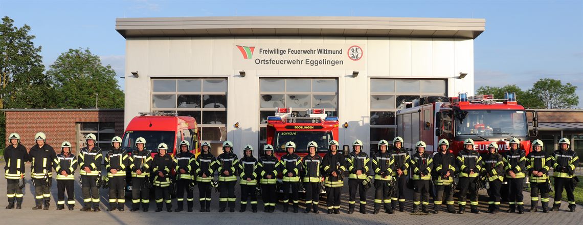 Die Einsatzabteilung der Ortsfeuerwehr Eggelingen in Einsatzkleidung vor dem Gerätehaus, dahinter die Fahrzeuge